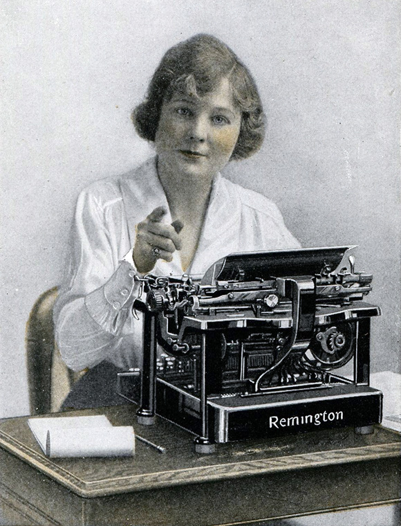 Remington typewriter ad from 1918 showing a woman seated behind a typewriter pointing forward.