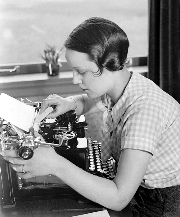 Woman seated, working at a typewriter, dated 1931.